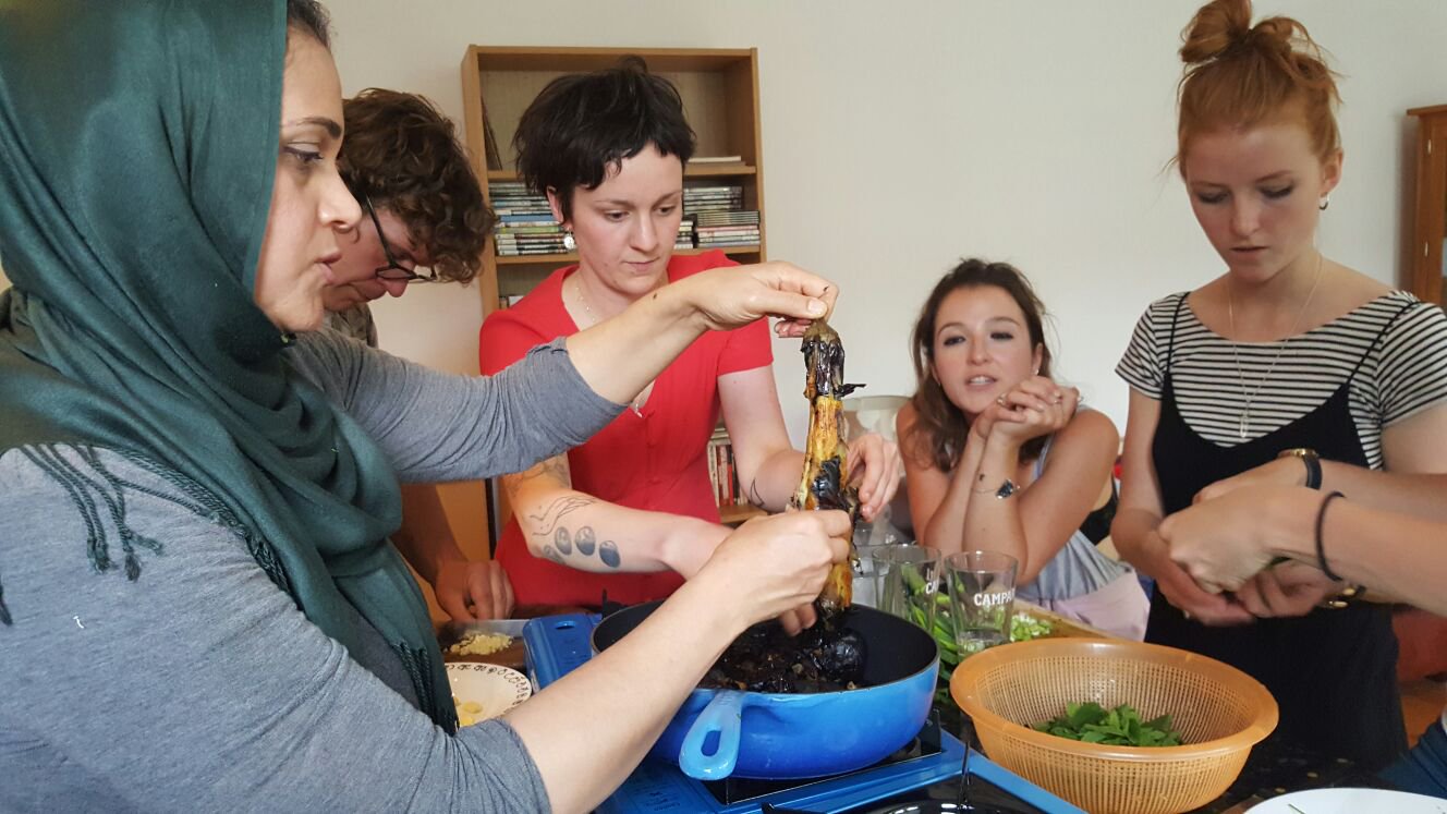 A group of people participating in a Migrateful cookery class in a London kitchen.