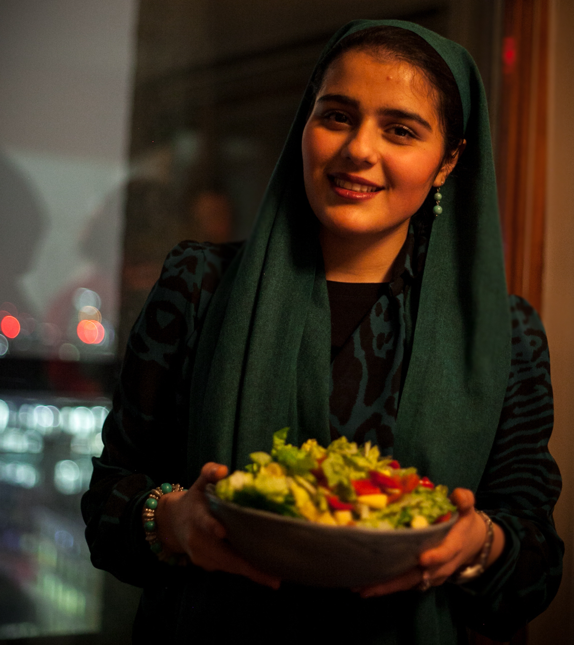 A woman holding a bowl of salad at a London Cookery Class organized by Migrateful.