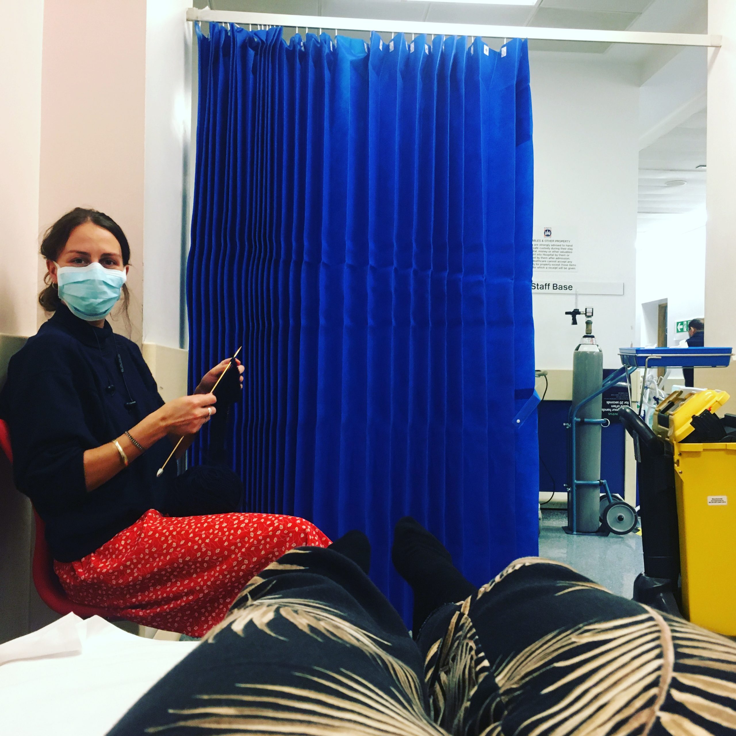 A woman wearing a face mask sitting in a hospital bed during the London Cookery Class.