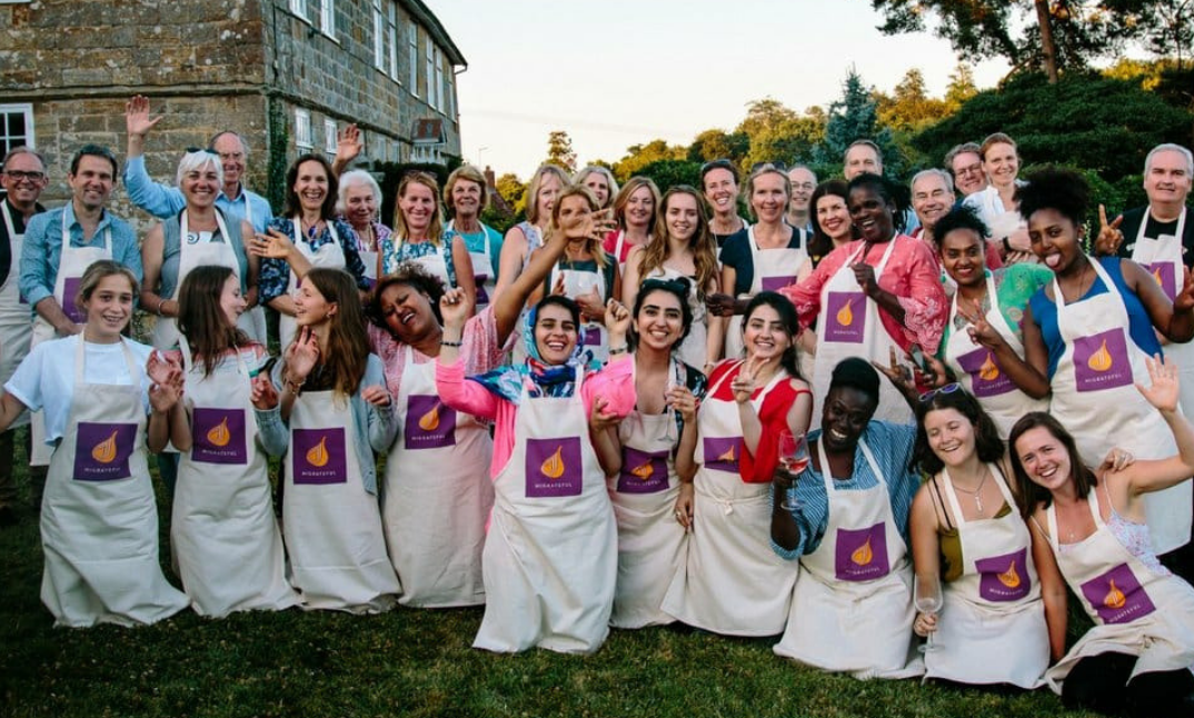 A group photo of volunteers wearing white aprons and greeting the camera