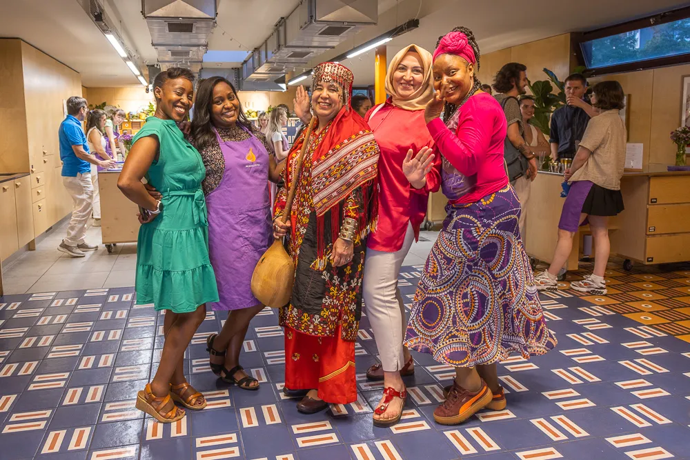 A group of women participating in a Migrateful London Cookery Class posing for a photo in a restaurant.
