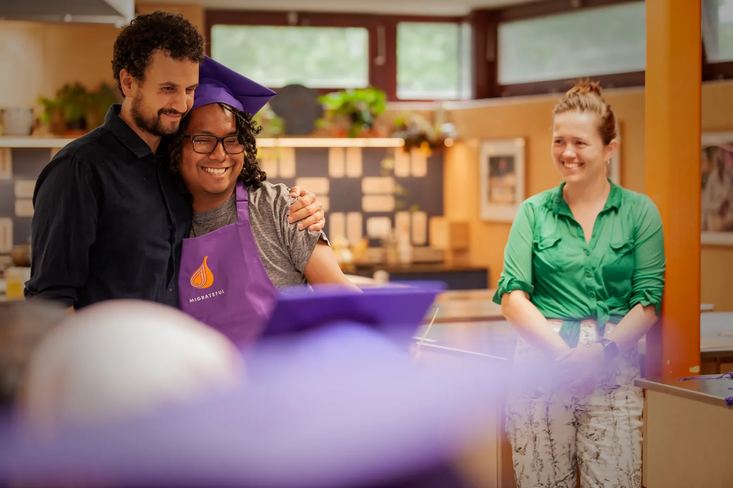 A group of people participating in a London Cookery Class at Migrateful, posing for a picture in a kitchen.