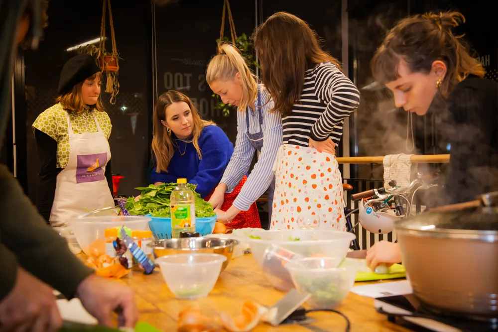 A group of people participating in a London Cookery Class, preparing food together.