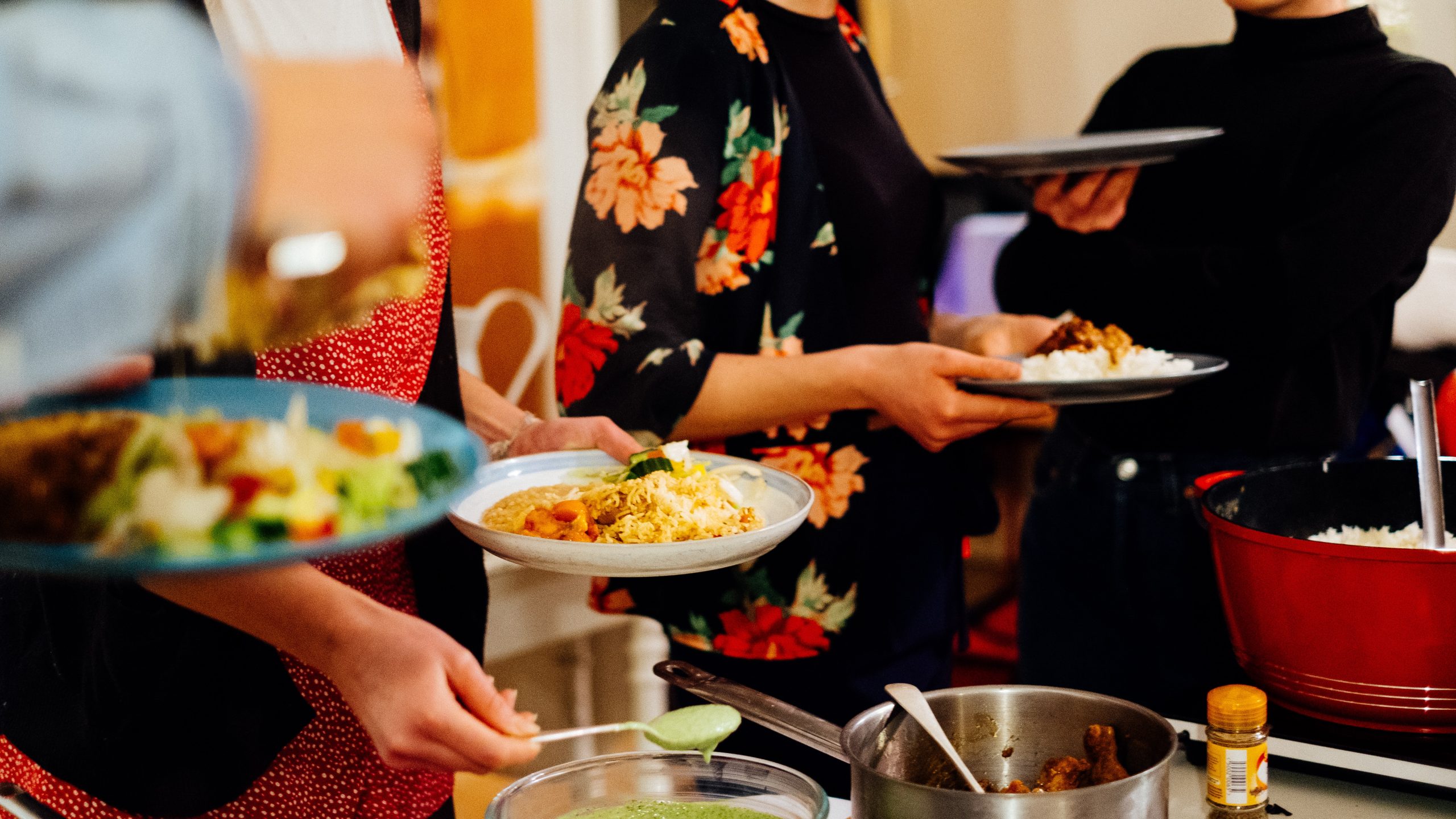 A group of Migrateful volunteers serving food at a London cookery class party.