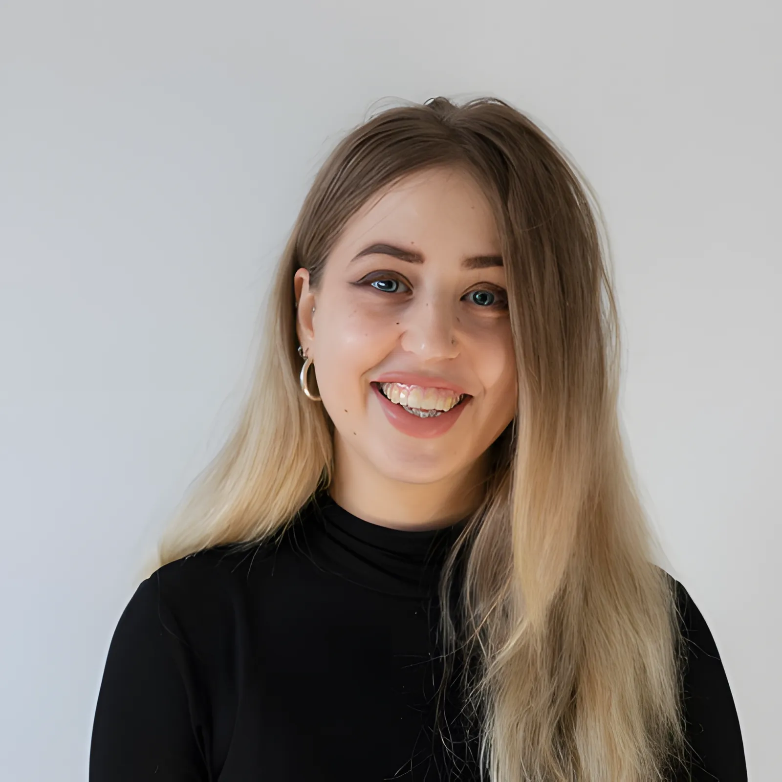 A woman with long blonde hair smiling in front of a white background at a London Cookery Class.
