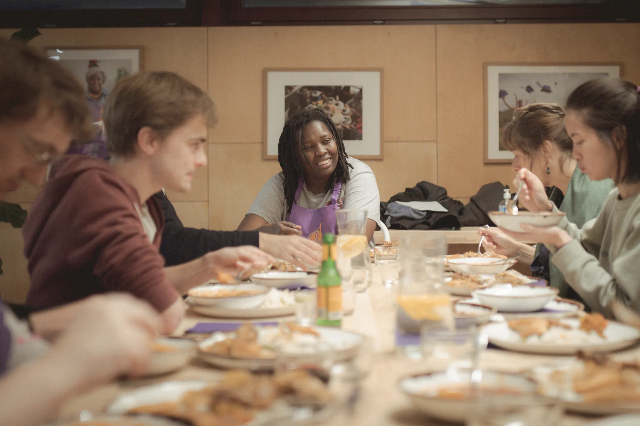 A group of people enjoying a Migrateful cookery class in London, gathered around a table while eating.