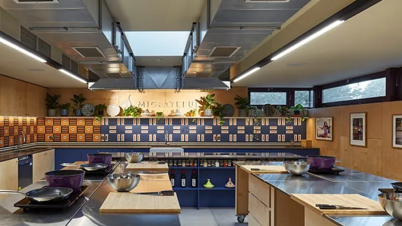 A Migrateful cookery class in London, hosted in a modern kitchen with blue counter tops and a skylight.