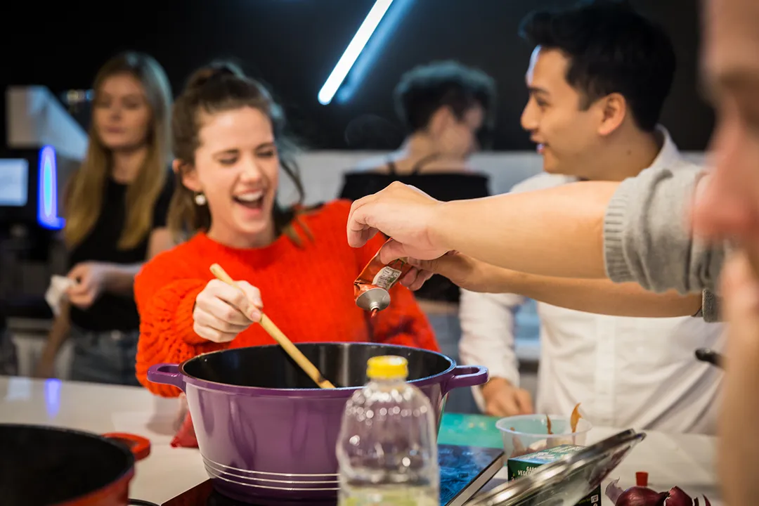 Migrateful hosts a London Cookery Class where a group of people come together to prepare food in a kitchen.
