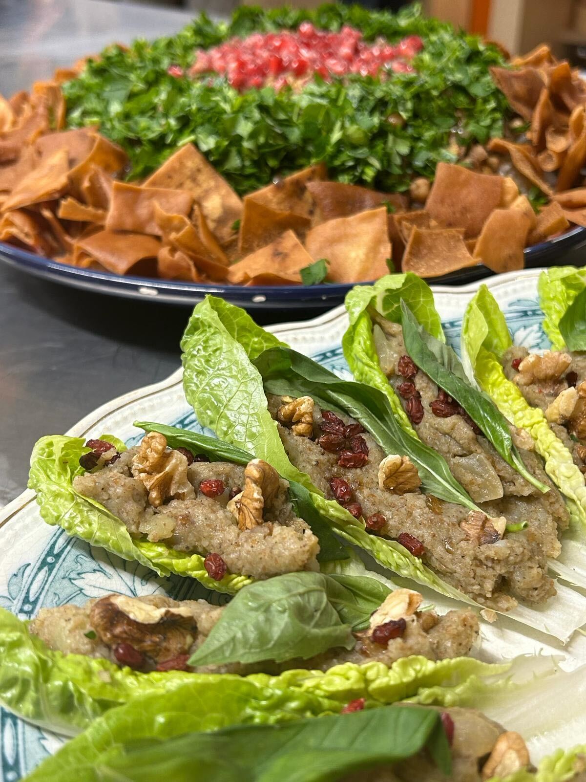 Two plates on a table, filled with chef Randa’s Malfouf (Stuffed Cabbage Leaves) and Fattoush (Arabic Bread Salad)