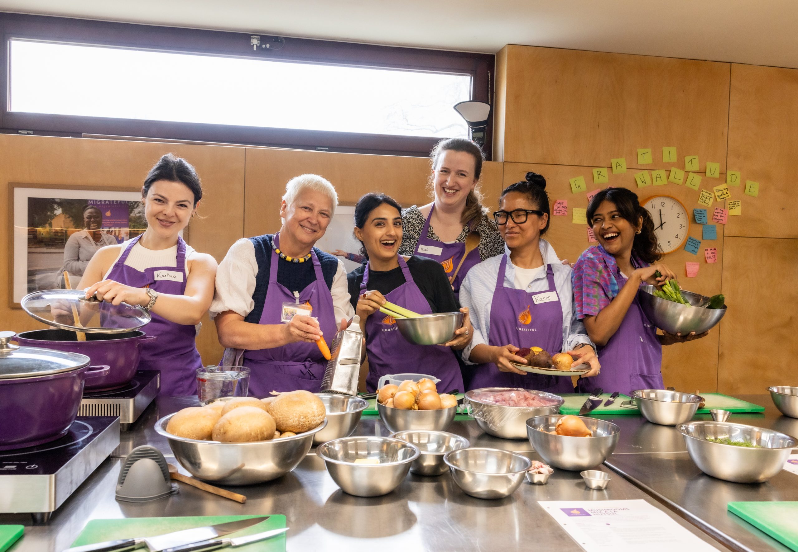 A group of volunteers wearing aprons stand holding pots and pans